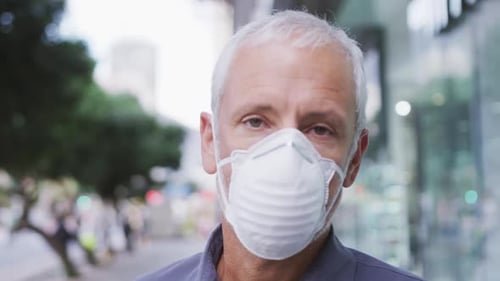 Caucasian man out and about in the street wearing on a face mask against coronavirus