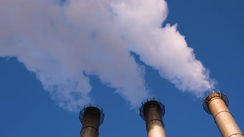Industrial Chimneys Releasing Smoke Against a Blue Sky