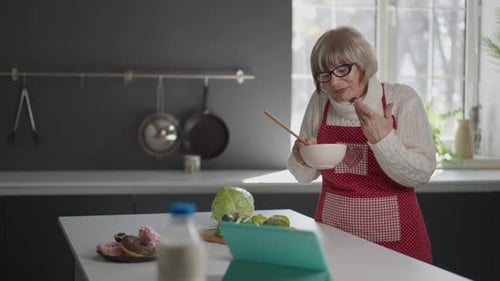 Woman Cooks in Kitchen Following Recipe on Tablet