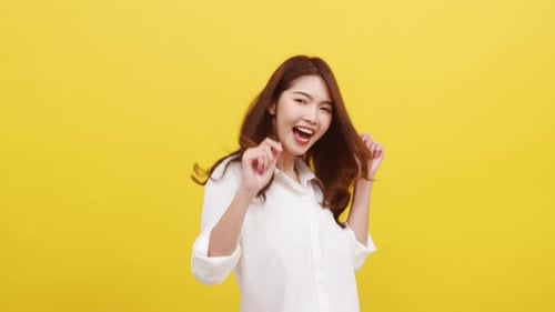 Woman Dancing Happily in Front of Yellow Backdrop