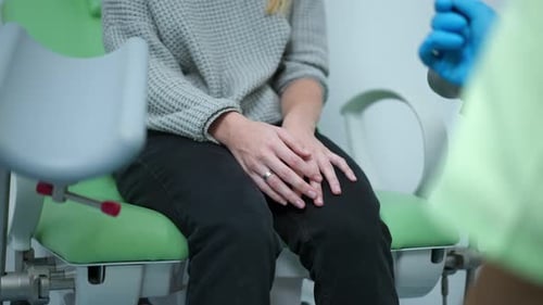 Woman Sits on Examination Table in Doctor's Office