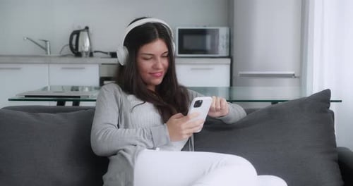 Süße Frau Textnachricht mit ihren Freunden oder Freund online, während sie auf der Couch sitzt
