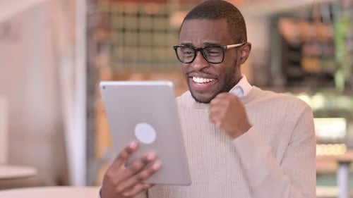 Excited Man Celebrates Success on Tablet Device