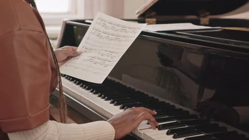 Young Adult Plays Piano and Reads Sheet Music