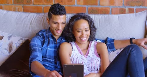 Smiling Couple Relaxing Together on Couch with Tablet