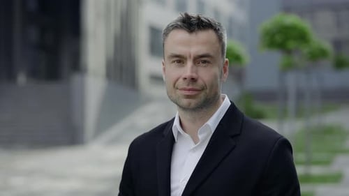 Smiling Businessman in Black Suit in Urban Setting