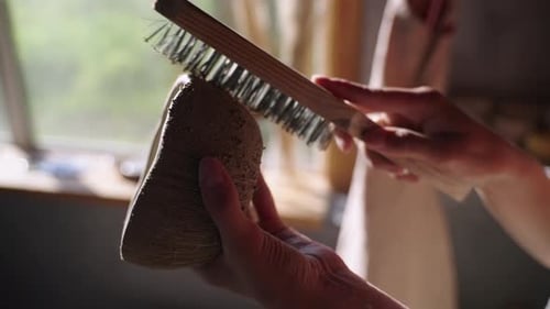 Person Brushing a Clay Creation in Studio