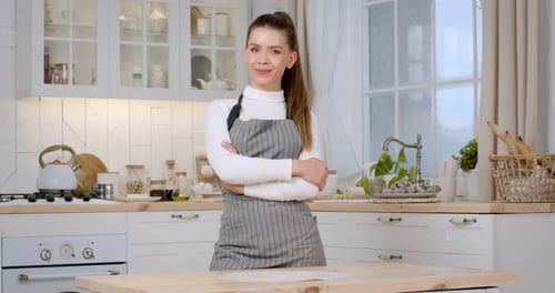 Smiling Woman Stands Confidently in White Kitchen