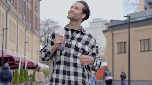 Smiling Man Walking with Backpack in City Street