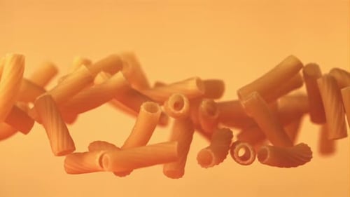 Rigatoni Pasta Pieces Levitating on Orange Background