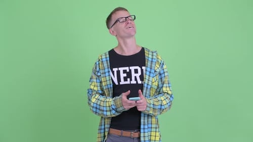 Young Man Using Phone, Thinking and Smiling