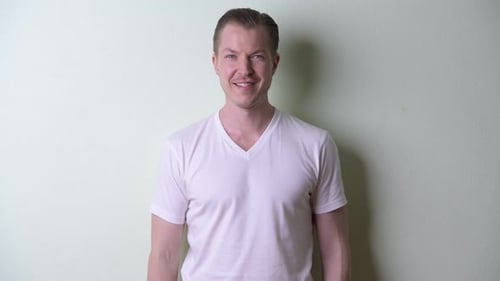 Glücklicher junger gutaussehender Mann mit blonden Haaren lächelnd