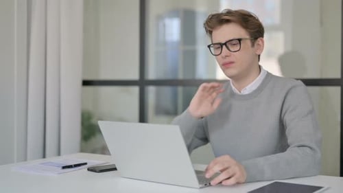 Young Man Having Neck Pain While Using Laptop in Modern Office