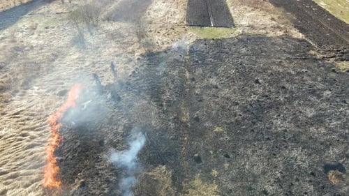 Aerial View of Firemen Extinguishing Grassland Field Burning with Red Fire During Dry Season
