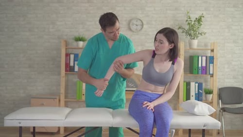 Physical Therapist Examines Arm of Young Adult Woman