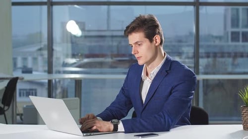 Young Adult Working on Laptop in Modern Office
