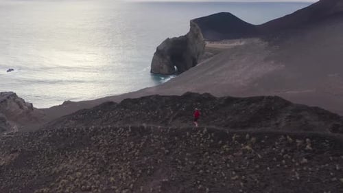Luftaufnahme eines rennenden Mannes mit einer Höhle im Hintergrund