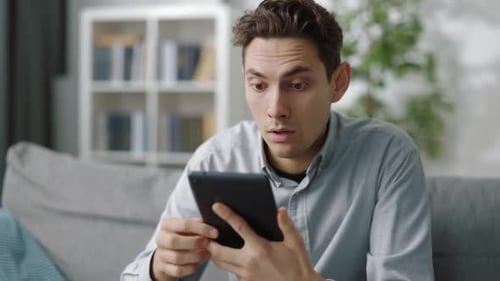 Man Uses Tablet on Couch Indoors