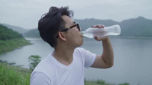 Hiker backpacker man on hiking adventure feeling freedom walking in forest near lake in rainy day.