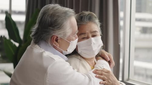 Senior Couple Hugging Wearing Medical Masks Indoors