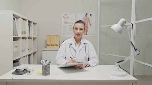 Woman Doctor Speaking and Taking Notes in Office