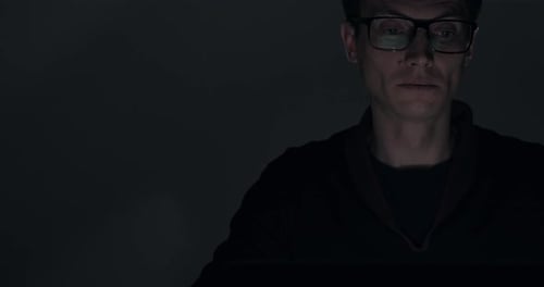 Portrait of a Man Working on Laptop Late at Night in Dark Room