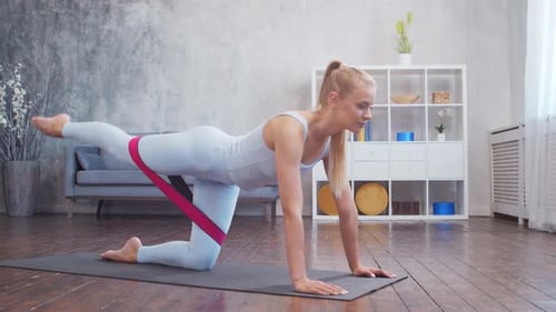 Woman Using Resistance Band for Leg Exercise at Home