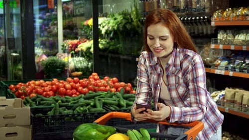 Woman Uses Smartphone While Grocery Shopping