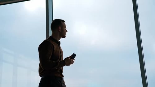 Handsome businessman writing notes from smartphone at modern office