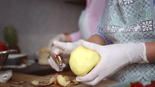 Woman Carefully Peels an Apple in the Kitchen