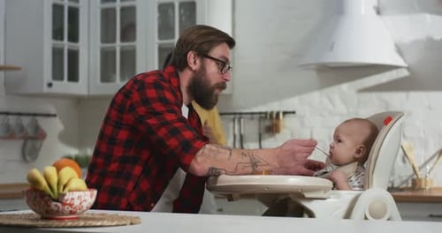 Loving Parents Feeding Baby in High Chair