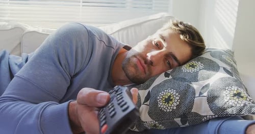 Young Adult Lying on Couch Using Remote