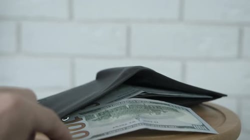 Hand pulls money out of full wallet