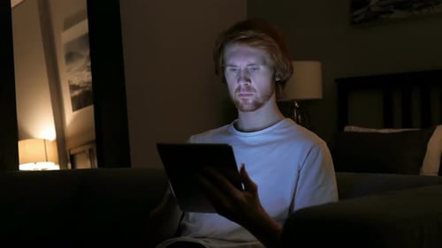 Redhead Man Using Tablet Computer at Night