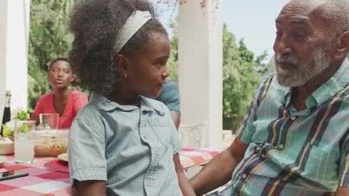Grandfather and Granddaughter Talking at Outdoor Table