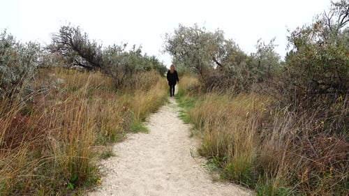Woman Walking Down Rural Sandy Path Away