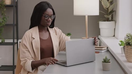 Empresária africana começando a trabalhar no laptop no escritório