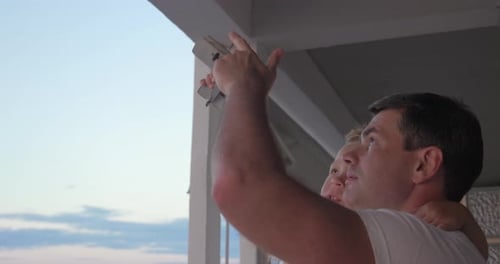 Father and Son Watch Sunrise with Toy Airplane