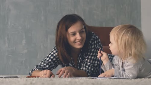 Woman and Child Drawing Together on Carpet
