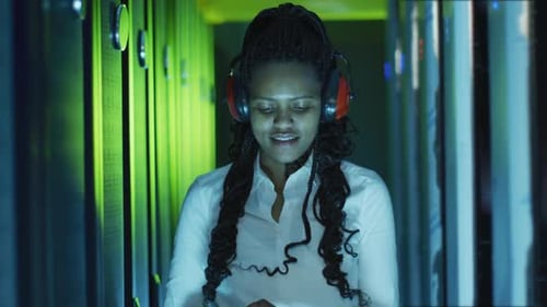 Young Woman Working in Server Room at Night