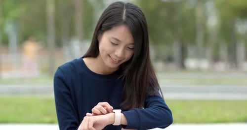 Woman Uses Smart Watch in City Park