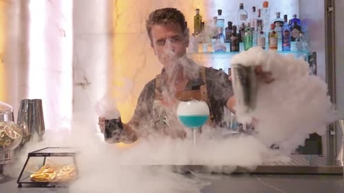 Young Adult Bartender Makes Steaming Cocktail at Bar