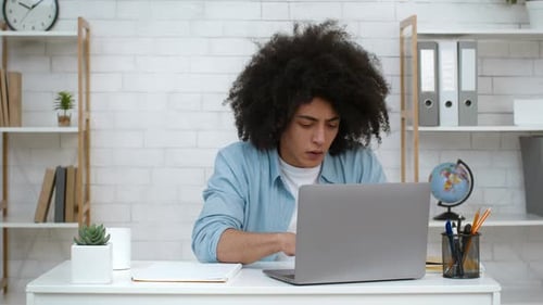 Young Adult Works at Computer in Home Office