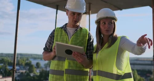 Construction Workers Review Plans on a Tablet