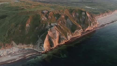 Beautiful Mountain Covered In Green Grass on the Shoreline of the Calm Ocean