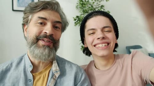 Smiling Father and Young Adult Wave During Video Call