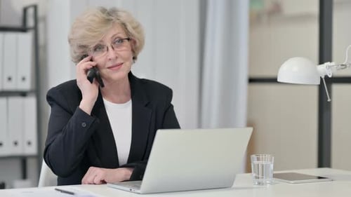 Woman Talking on Phone at Desk with Laptop