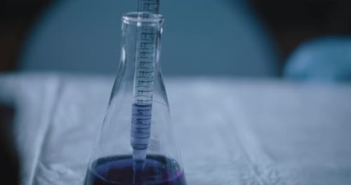 Scientist put a purple liquid into a conical flask in a lab,slow motion,tracking