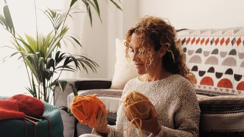 Woman Knitting Red Yarn Indoors During the Day