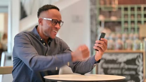Excited Young Adult Using Smartphone Indoors